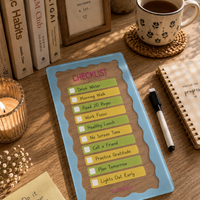 Desk with a checklist, coffee mug, books, and candles on a wooden surface.