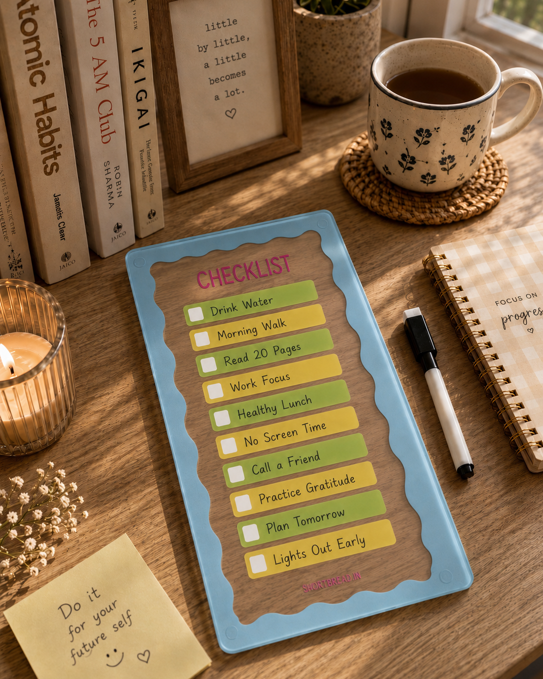 Desk with a checklist, coffee mug, books, and candles on a wooden surface.