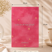 A pink notebook with gold stars and the text 'to live for the hope of it all' by SHORTSBREAD.IN, shown with dimension markers indicating 14 cm width and 21 cm height, on a styled beige background with a vase of flowers and a cup.